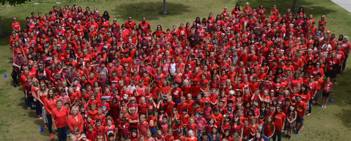Students dressed in red forming the shape of a heart.